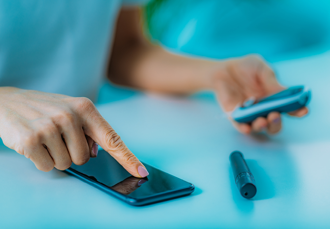 woman checking blood glucose with meter and pen and smartphone on blue background