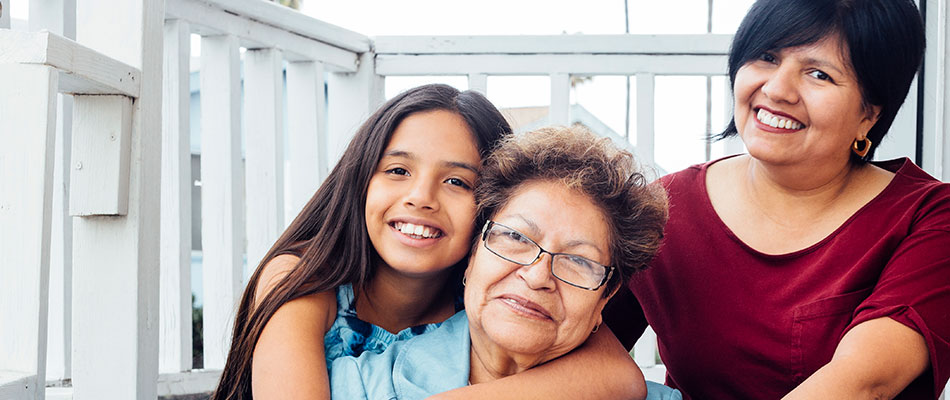 Smiling Latino grandmother, daughter, and granddaughter on steps