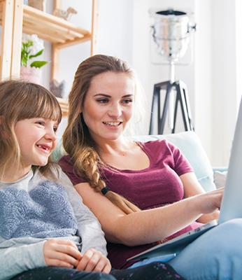 Mom and daughter on couch looking at computer