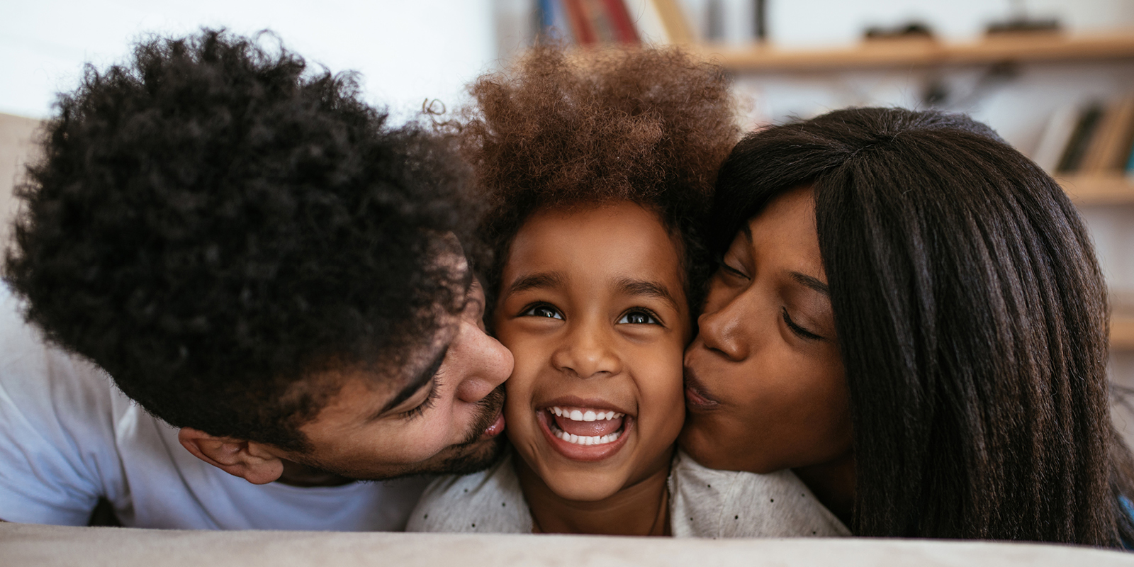 Young African American couple kissing girl on cheek