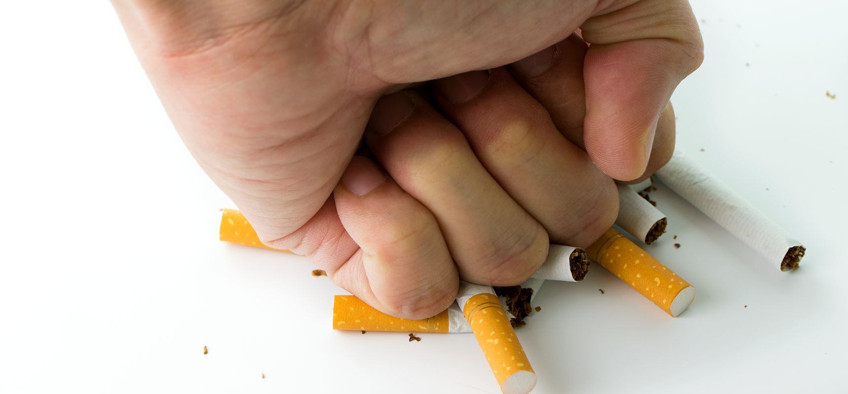 Balled fist punching down on pile of cigarettes signifying quitting smoking