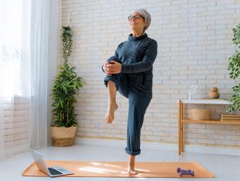 senior woman standing on yoga mat and lifting leg