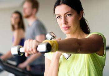young in woman green shirt exercising with chrome dumbbells