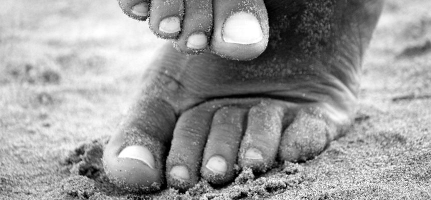 African American bare feet in sand