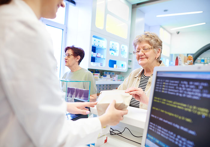 pharmacist-handing-medications-to-senior-woman-customer