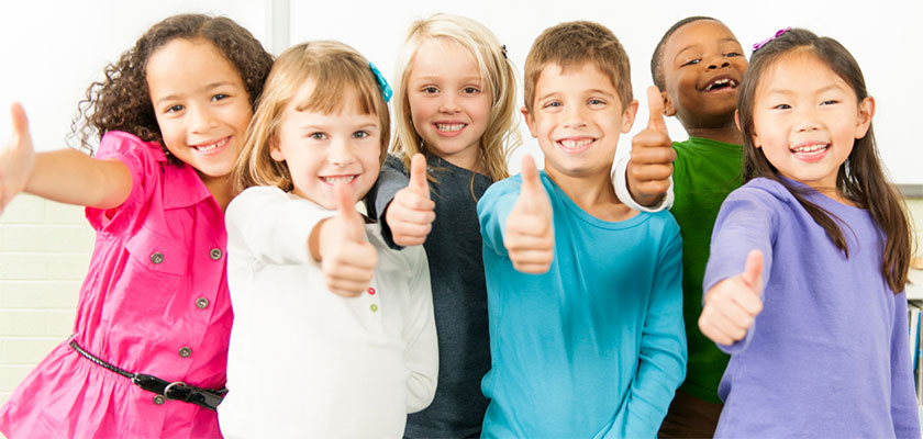 Mixed group of smiling elementary school children giving a thumbs up