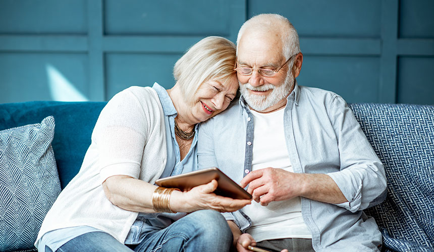 Senior couple on couch looking at tablet computer.